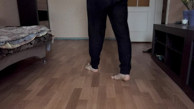 The man walks around the room from side to side. Focus on the legs