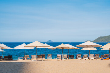 beach umbrellas with sun beds on a sandy beach against the background of the sea or ocean. Without people