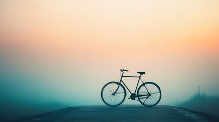 Silhouette of bicycle on foggy road at sunrise