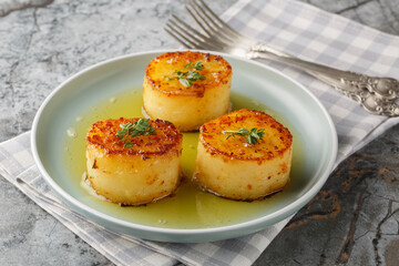 Garlic Thyme Fondant melting Potatoes are velvety on the inside and crispy on the outside closeup on the plate on the table. Horizontal