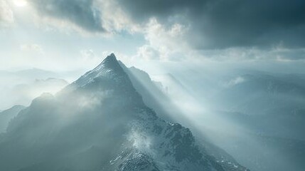 A tranquil mountain peak shrouded in mist, with sunlight breaking through the clouds and casting a heavenly glow over the rugged terrain below.