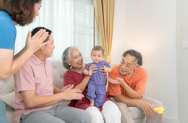 Grandparents and parents with their little child play happily in the living room of the house