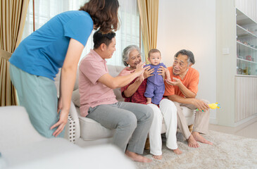 Grandparents and parents with their little child play happily in the living room of the house