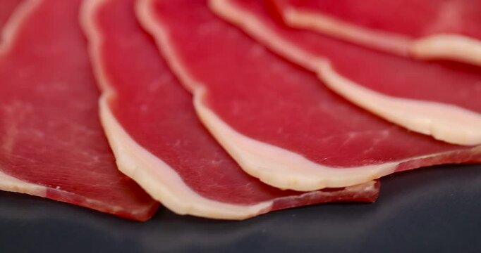 sliced ham with bacon on a board, thinly sliced pork ham from a fillet for serving a festive table
