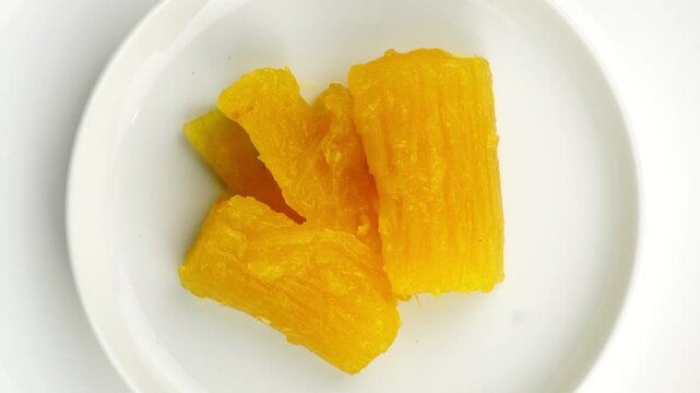 Top view of cassava in syrup in white ceramic dish rotated on white background