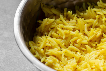 Pilau rice, used with Indian curry dishes, in a metal bowl dish.  On a grey concrete background