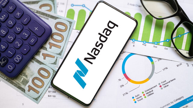 NASDAQ logo on phone screen with money, calculator and financial documents background. London, UK, 08.28.20204