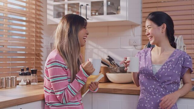 Asian beautiful women friends drink a cup of coffee together in kitchen. 