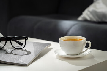 A Cup of Coffee, Glasses, and a Stack of Magazines on a White Tabletop