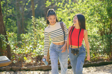Fototapeta premium Cheerful Asian travelers walking in park and chatting