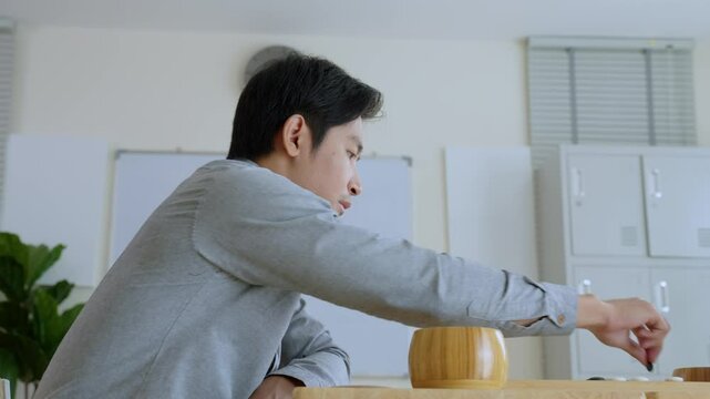 Asian young men playing board game Go during competition in community. 