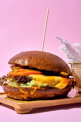 A classic American-style hamburger on a sesame seed bun, topped with fresh vegetables and served with a side of crispy fries.