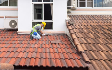 Worker man using waterproof roof coating repair to fix crack of the old tile roof. © toa555