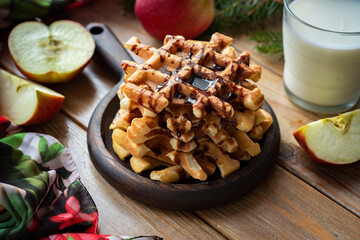 Sweet dessert for breakfast: Viennese waffles with chocolate syrup on a plate on a wooden table. Close-up.