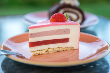 A slice of cake with a strawberry on top sits on a plate