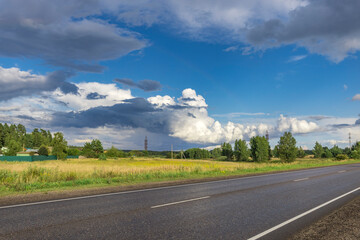 A road with a few trees in the background and a cloudy sky