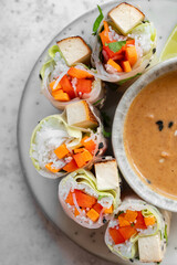 Summer rolls with fresh vegetables and smoked tofu served with peanut sauce and lime. Vietnamese appetizer. Spring rolls. Healthy food concept. Snacks, finger food. Close up.