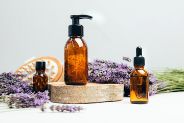 Set of natural cosmetics. Amber bottles with facial, bath liquid on a concrete background with lavender flowers. Front view