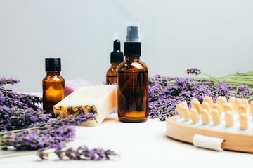 Set of natural cosmetics. Amber bottles with facial, bath liquid on a concrete background with lavender flowers. Front view © Olha