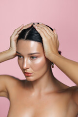 Fototapeta premium Natural Beauty Latina Woman Posing with Hands on Head Against Pink Background