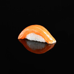 Close-up of a delectable salmon nigiri sushi garnished with a delicate topping, isolated on a dark background