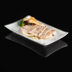 Grilled Sea Bream Dorado fillets served on fresh salad. Black background. Top view.