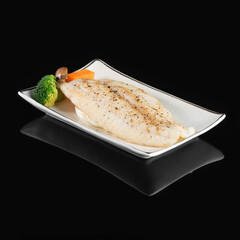 Grilled Sea Bream Dorado fillets served on fresh salad. Black background. Top view.
