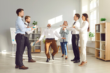 Office workers, colleagues and coworkers, are playing the limbo game and dancing at an office party...