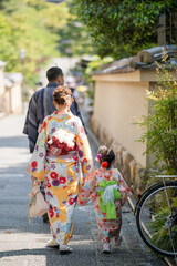 Unidentified woman with a child wearing Japanese kimono walking on the street.