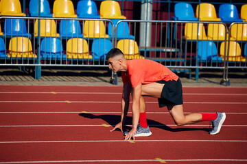 Side view photo of young man, ready to run standing on start line in low start position. Training...