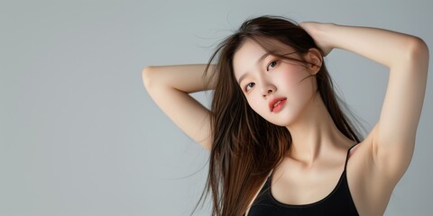 Obraz premium Young woman posing gracefully with long hair against a neutral background while showcasing elegance and style