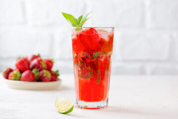 Strawberry mojito lemonade with ice, lime and mint in glass on white table. Cold summer drink. Sugar free, nonalcoholic.