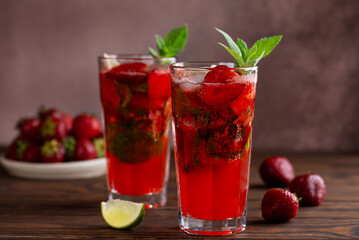 Strawberry Mojito cocktail with lime, ice and mint on a wooden table. Sugar free, nonalcoholic.