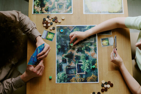 From above view shot of unrecognizable couple sitting at wooden table playing fantasy board game