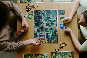Top-down shot of young man and woman playing modern roll-and-move fantasy board game © AnnaStills