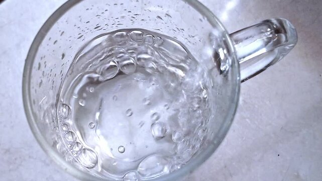 Vaso llenandose de agua en un fregadero de acero inoxidable