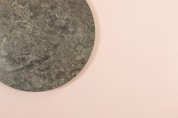 Top view of brown marble plate on pink background. Food presentation, stone tray. Copy space, flat lay.