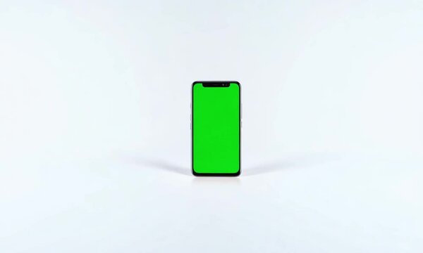 Mockup of Cell Phone with Green Blank Screen on White Background with Zoom In-Out Footage