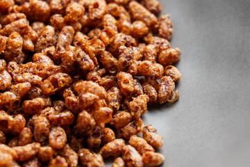 Chocolate crispy rice breakfast cereal flakes scattered in a black plate close up