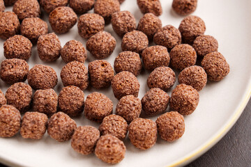 Cereal brown chocolate balls or crunchy breakfast corn flakes in kitchen ceramic plate.
