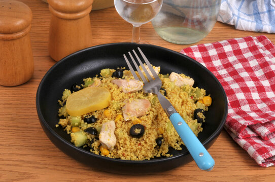 Assiette de semoule estivale avec des morceaux de poulet, des olives noires, du ma&iuml;s et une rondelle de citron confit