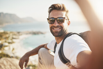 Man, hiking and sunglasses selfie on mountain top, backpacking adventure and capture memory. Male person, hand and social media post for travel blog in nature, Bali and ocean view on holiday trip