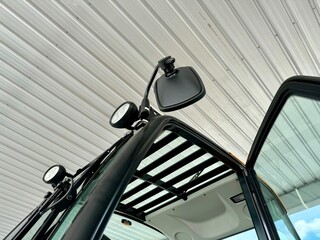 Close-up of a Tractor's Mirror and Cab Roof: A detailed view of a modern tractor's side-view mirror, cab roof, and door, showcasing the sleek design and functionality of agricultural machinery.  