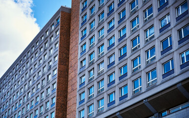 Fototapeta premium Pattern of square windows on modern building shows a modern lifestyle in crowded contemporary apartments. Concrete exterior conveys real estate and rental crisis in capital cities like Berlin, Germany