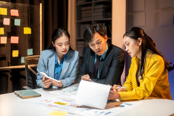 Three people are sitting at a table, looking at a laptop