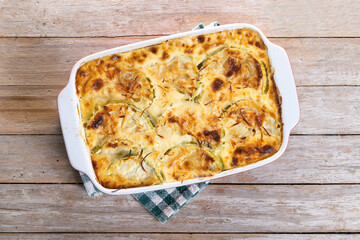 Casserole with cheese and gratin zucchini on wooden table. Top view