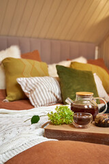 on the bed in a modern bedroom is a tray with a kettle and cups