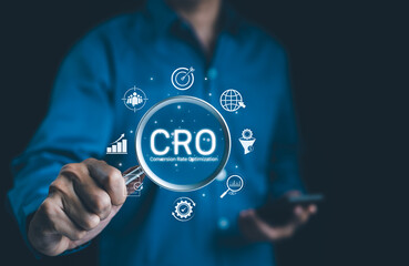 CRO, Conversion Rate Optimization Concept. Businessman holding magnifying glass focusing on the text 