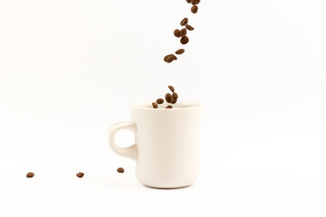 Coffee beans are pouring into a white ceramic cup