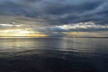 Calm sea meeting a cloudy sky at the horizon during sunset